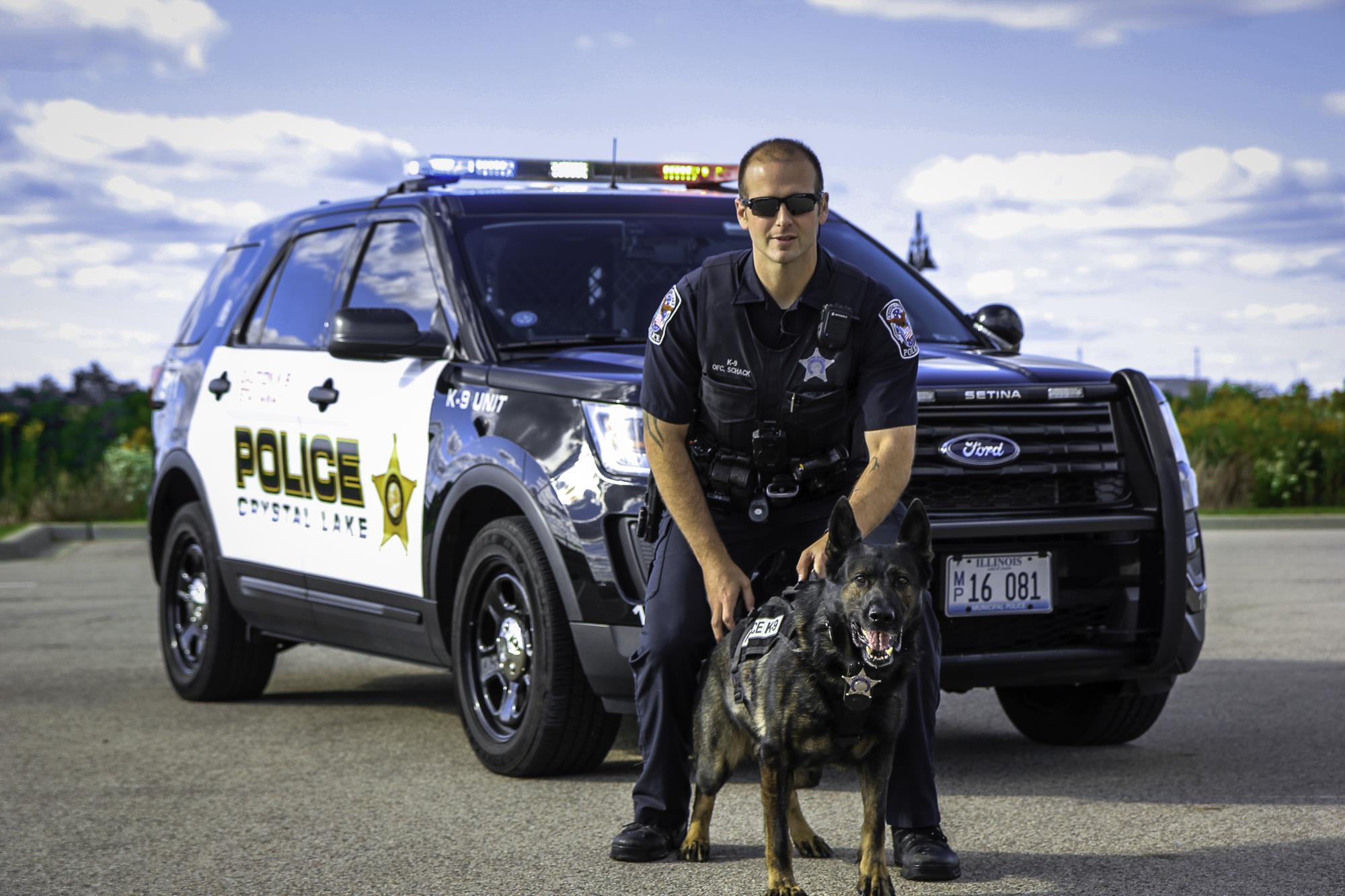 Officer Schack with German Sheppard Zeus in front of squad car